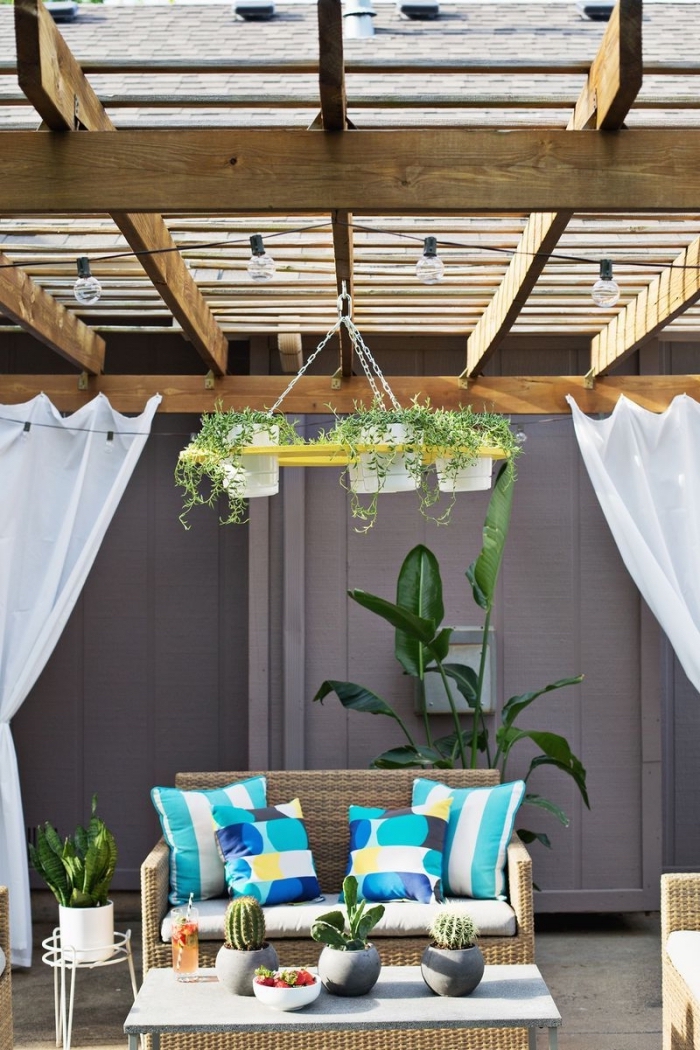 idée comment aménager son extérieur avec meubles en rotin et plantes vertes, exemple porte pot de fleur à design chandelier