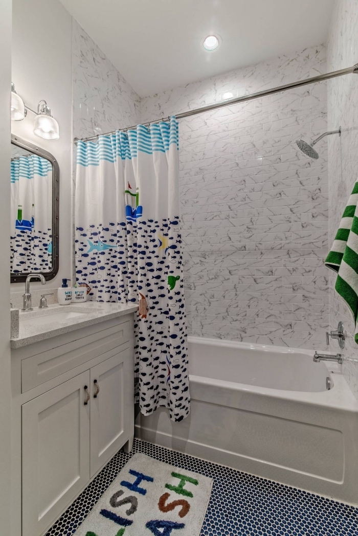 agencement salle de bain petit espace avec baignoire enfant et rideaux de douche aux motifs marines en blanc et bleu