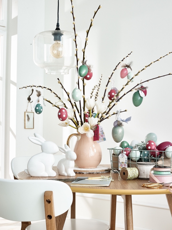 idée activité paques facile, bouquet de branches décorés d'oeufs dans un vase rose pastel, modèle centre table diy pour Pâques