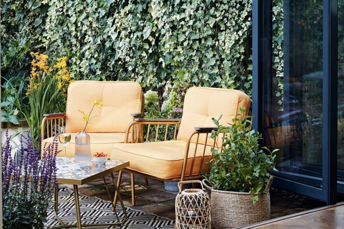 Fauteuils jaunes deco terrasse, aménagement terrasse de jardin option extérieur fleurs violets et oranges, tapis géométrique noir et blanc