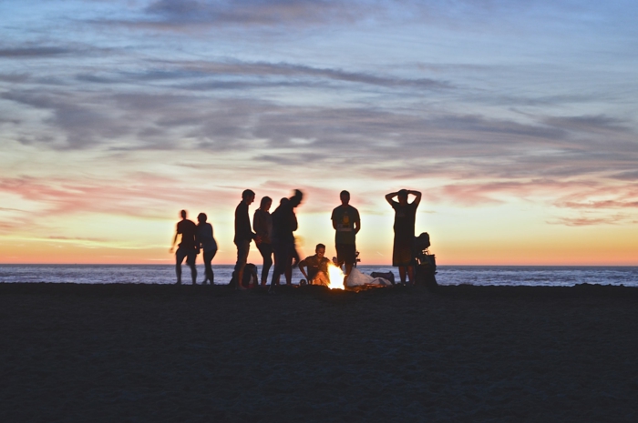 Soirée autour le feu à la plage, photo amis amusement au coucher de soleil au bord de la mer, organisation enterrement de vie de garçon 