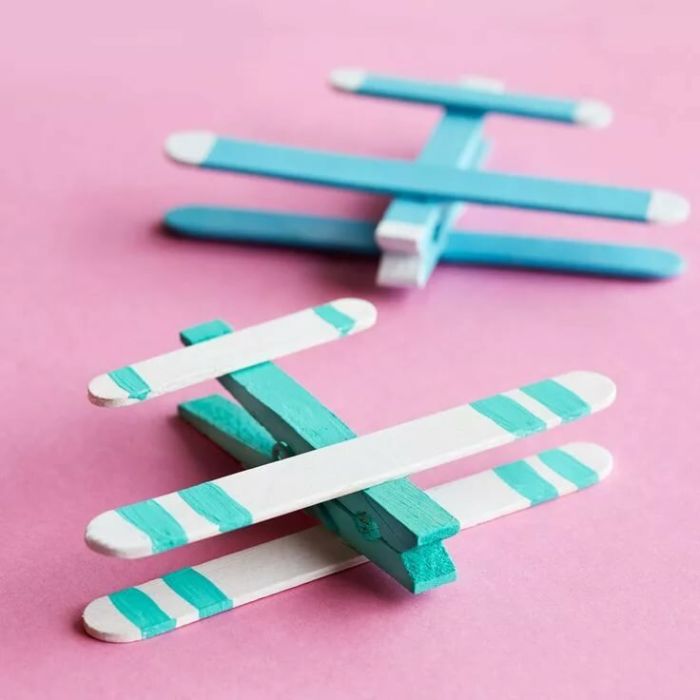 pince à linge et des batonnets de glace pour bricoler un avion en bois simple coloré de bleu, activité manuelle primaire pour garçon
