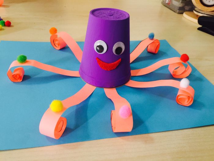 pieuvre fabriquée dans gobelet en plastique repeint de violet avec des tentacules de papier et de syeux mobiles, activité manuelle été
