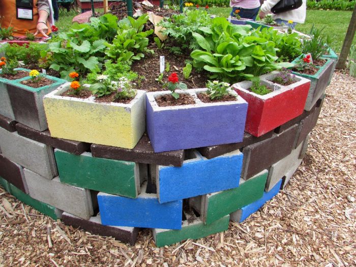 comment faire un jardin exterieur, lit de fleurs composée de jardinieres de beton repeintes de couleurs variées