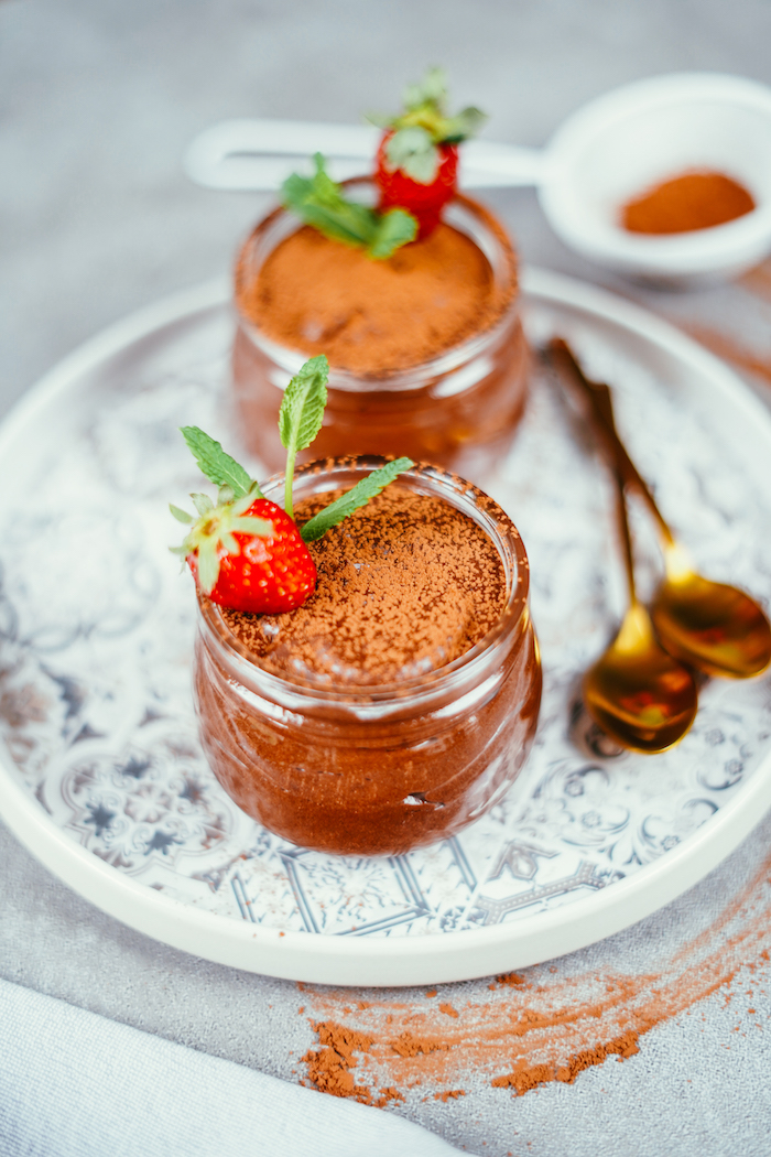 pots de verre remplis de mousse au chocolat maison avec chocolat noir et aquafaba et décoration de poudre de cacao, fraise, menthe