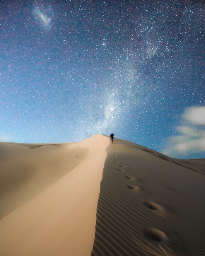 image fond d écran pour téléphone portable, photo voyage avec un homme qui se promène dans le désert sous ciel étoilé