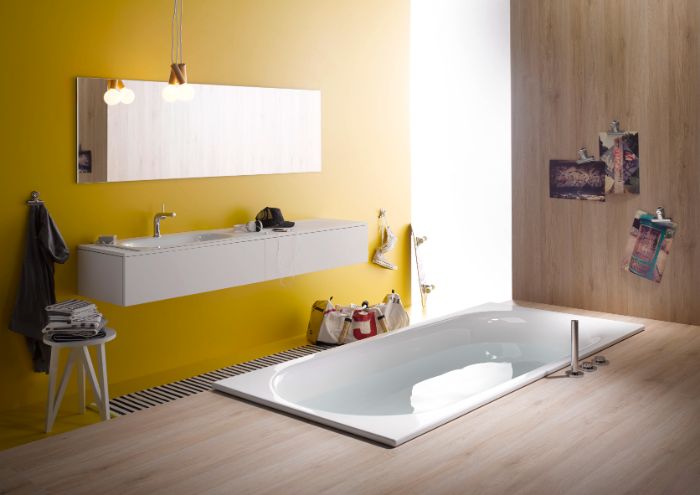 peinture murale salle de bain couleur jaune avec miroir rectangulaire et meuble blanc, revetement sol bois, baignoire encastrée dans le sol