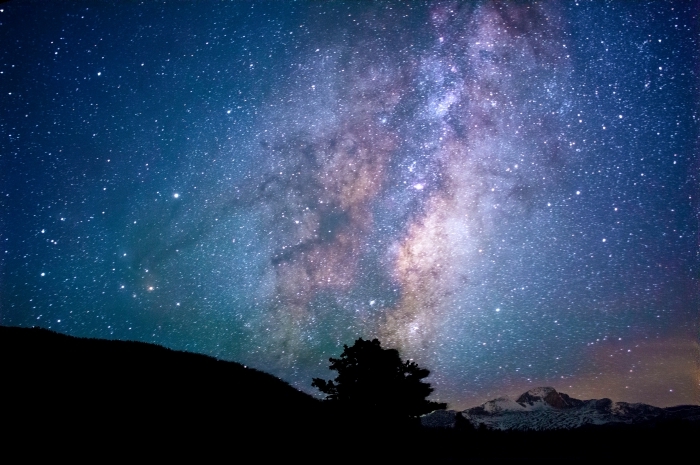 fond d écran stylé pour personnaliser son ordinateur, image galaxie avec ciel nocturne et silhouette de montagnes et arbre