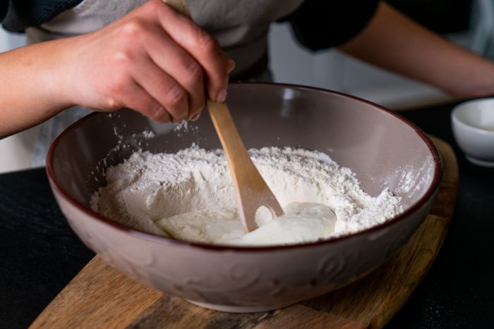 incorporer la farine dans le yaourt, etape pour faire pate a pain nann simple à cuire à la poele