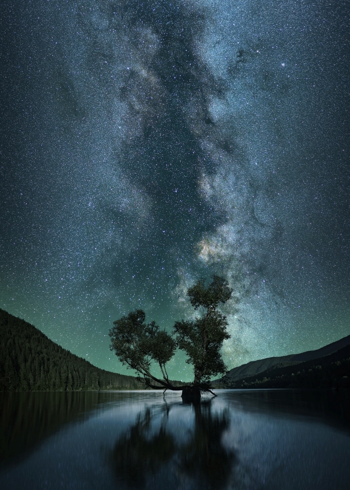 paysage fond d écran nocturne avec sommets de montagnes et reflets de silhouettes d'arbres dans un lac sous le ciel étoilé