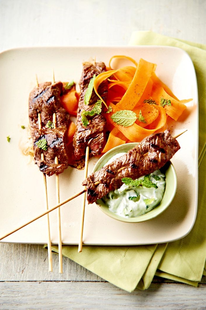 idee brochette de viande grillée de boeud à la sauce tzatziki et des carottes dans une assiette blanche