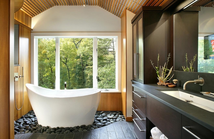 agencement salle de bain asiatique avec petite baignoire autoportante sur un jardin aux cailloux gris, déco salle de bain en blanc gris et bois