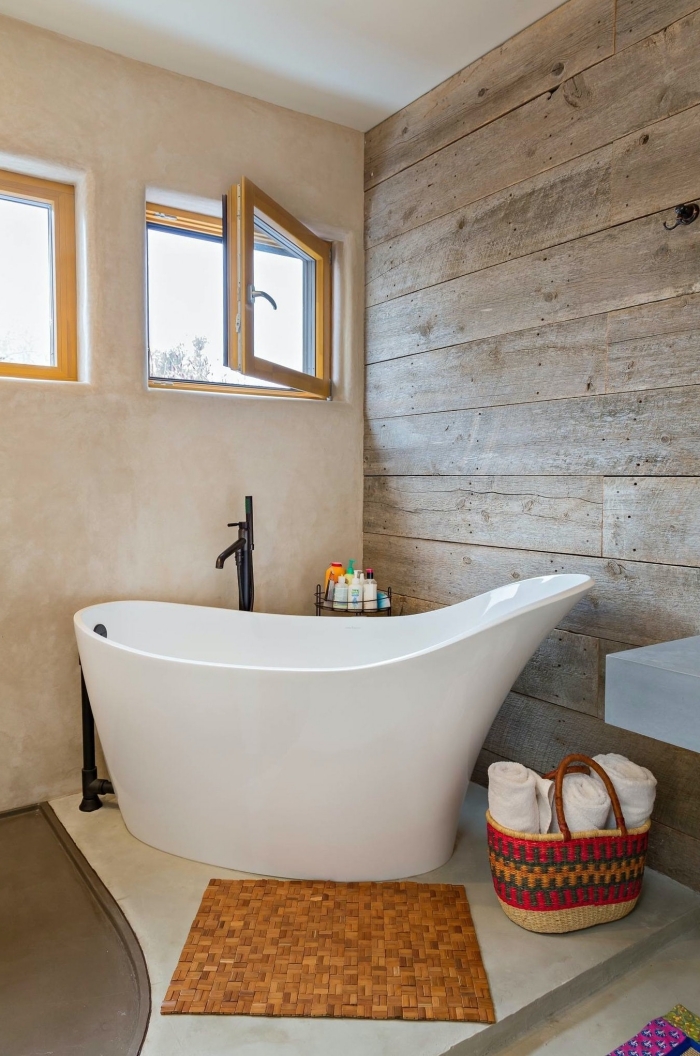 modèle de baignoire sabot autoportante dans une petite salle de bain aux murs à effet bois et sol en blanc et gris