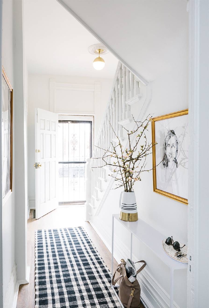 aménagement entrée étroit tapis blanc et bleu motifs carreaux cadre peinture doré photo blanc et noir déco sous escalier moderne