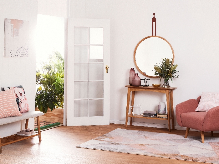 design intérieur tendance aménagement entrée avec meubles en bois peinture couloir blanc accents en rose fauteuil miroir rond