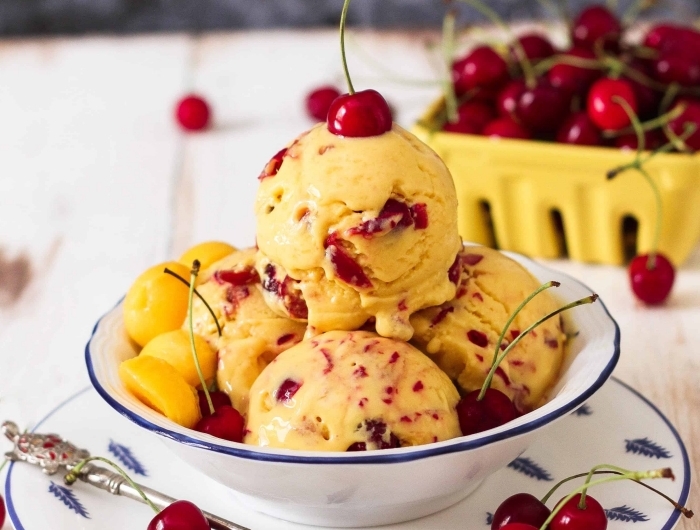 dessert frais pour l été préparation crème glacée aux fruits recette fruit tropicale crème glacée à la mangue et cerises assiette blanche feuilles bleues
