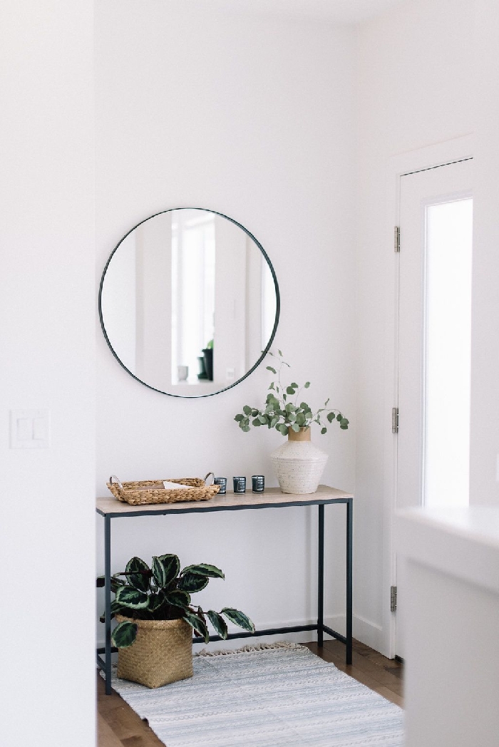 déco entrée maison style minimaliste intérieur déco scandinave couloir blanc meubles métal noirci panier tressé tapis franges miroir rond