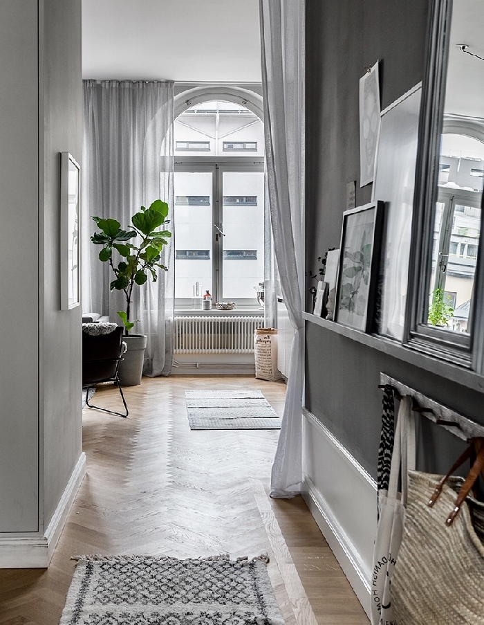 décoration entrée appartement style parisien rideaux longs blancs revêtement de sol parquet bois plante verte cadres miroir tapis franges