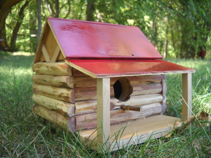 assemblage de morceaux sous forme de cabane oiseaux originale avec toit rouge et petite terrasse en bois