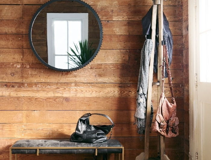 miroir rond cadre métal noirci banquette or et velours gris anthracite déco entrée maison style rustique revêtement mural bois foncé