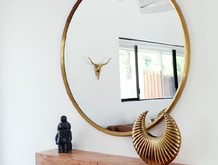 miroir rond cadre or decoration couloir moderne murs blancs meuble bois rangement accessoires décoratifs objets statuette plante verte