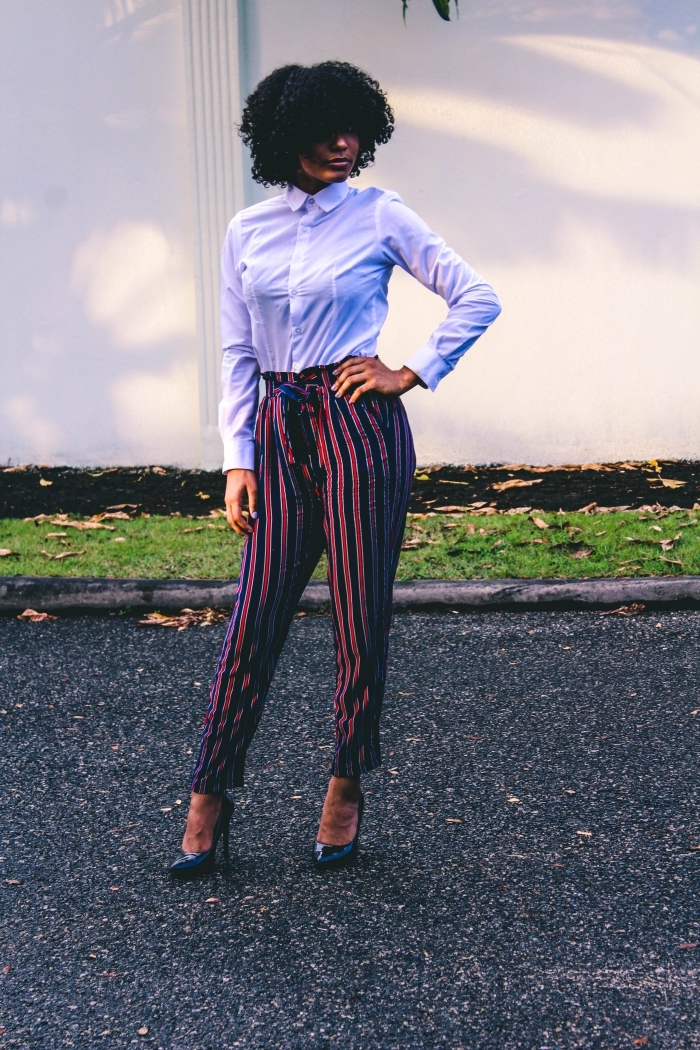 pantalon taille haute en rouge et bleu foncé chaussures à talons bleues coupe afro femme coiffure volume cheveux noirs chemise blanche femme