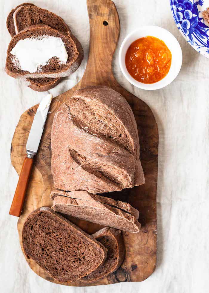 pain complet avec de la farine complète à déguster avec beurre et confiture, pain sur planche à découper