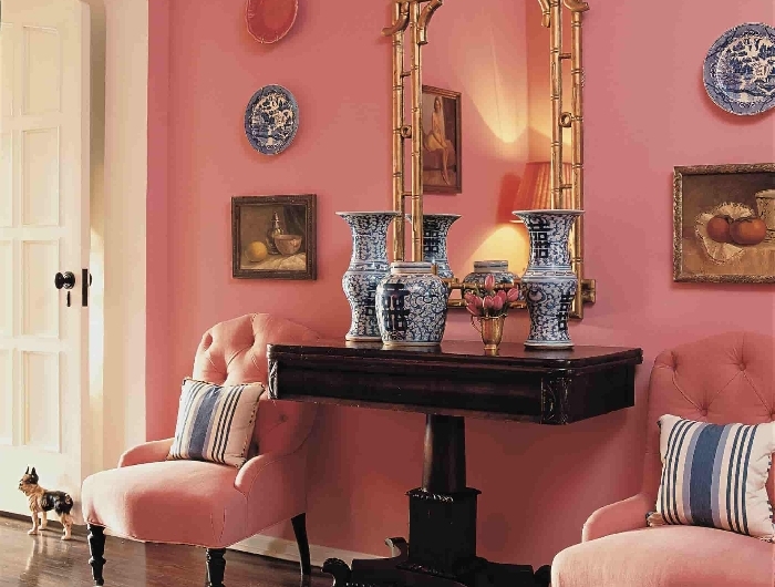 peinture murale rose aménagement entrée maison fauteuil tissu boutonné rose meuble bois foncé cadre miroir or tapis imitation zèbre