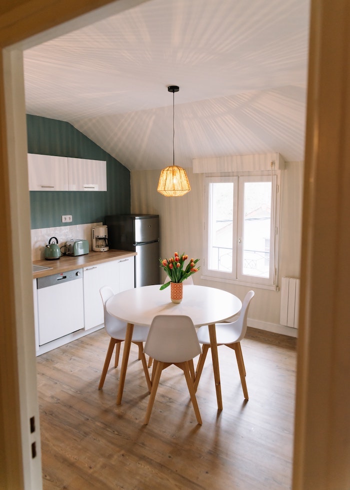 Table à manger ronde, chaises blanches, mur vert tendance cuisine 2020, peinture salle a manger qui donne à la cuisine