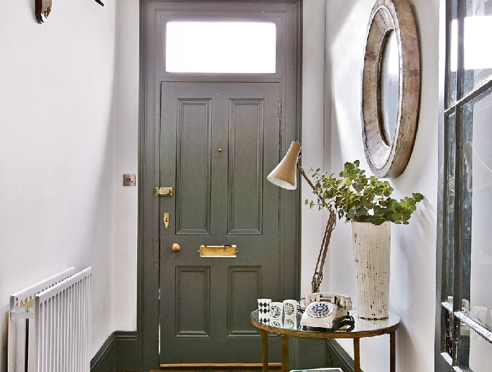 porte grise poignée or miroir pierre aménager une entrée de style rustique cornes décoratives parquet bois foncé table ronde or