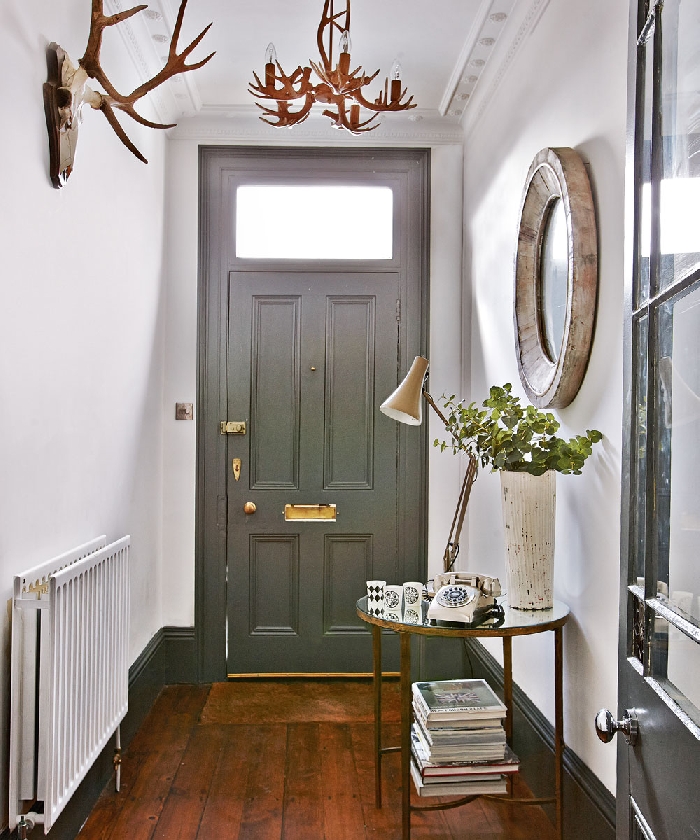 porte grise poignée or miroir pierre aménager une entrée de style rustique cornes décoratives parquet bois foncé table ronde or