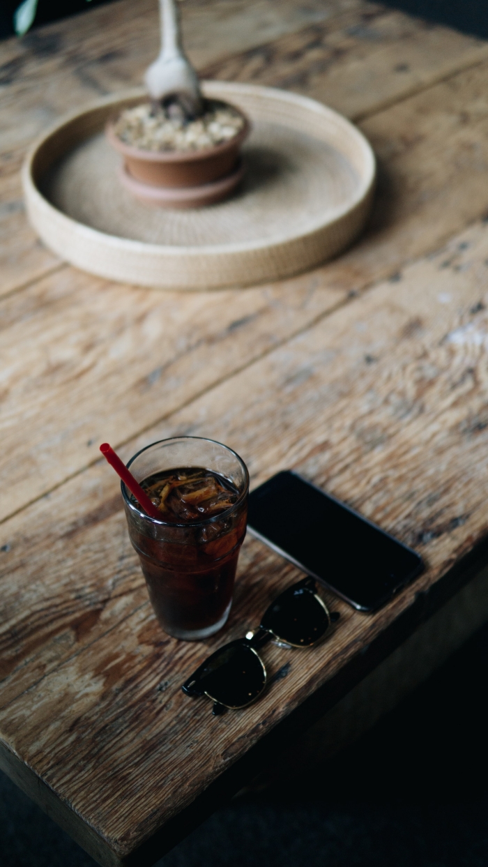 idée comment préparer une chicorée boisson originale, verre rempli de café noir avec glaçons sur une table bois brut