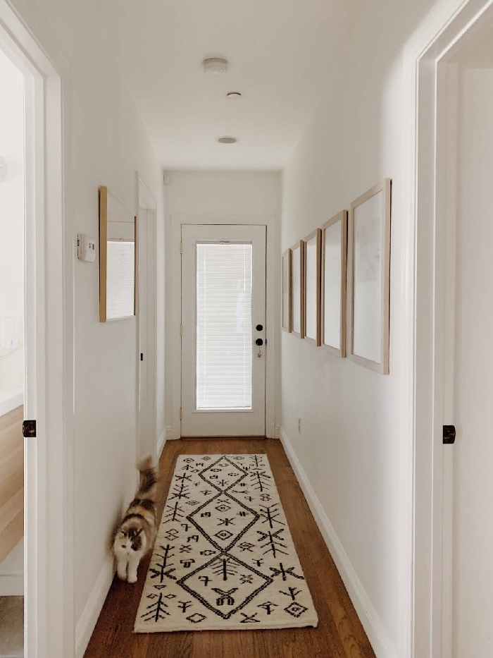 tapis blanc et noir motifs aménager une entrée étroite de style minimaliste cocooning cozy intérieur couloir mur de cadres bois