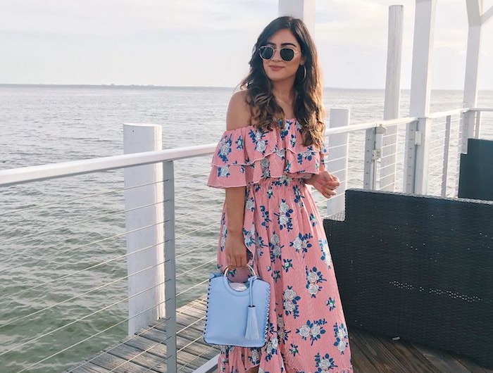 vacances au bord de la mer belle robe longue rose sac a main bleu claire et robe fleurie femme robe d été fleurie pour femme romantique fille cheveux bouclés lunettes de soleil ray ban