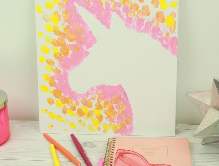 activité manuelle 4 ans idée de peinture enfant avec des empreintes de doigt couleur rose orange et jaune sur panneau couleur blanche avec motif licorne