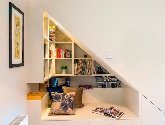 banc de lecture sous pent mur aux étagères blanches avec des livres coussins colorés idee deco cosy