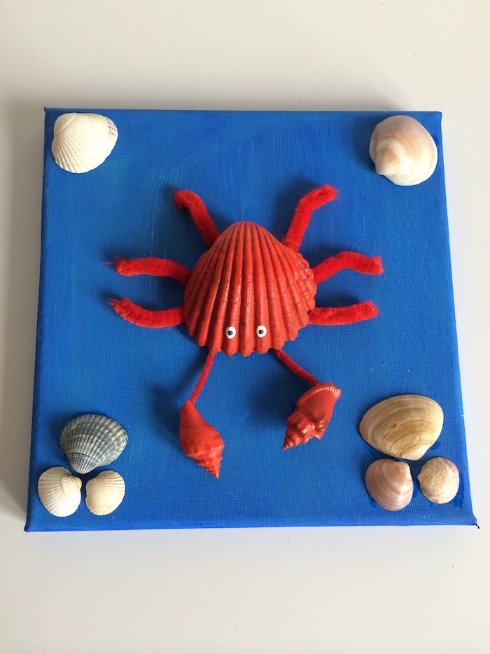 canevas repeint en bleu avec décoration de coquillages de mer et crabe en coquillage et cure pipe activité manuelle été enfant