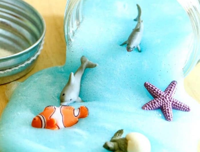 comment faire du slime maison couleur bleue imitation bord de mer avec des figurines de poisson et étoiles de mer et autres créatires marines activite enfant 4 ans