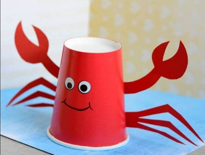 crabe diy en gobelet de plastique de couleur rouge avec des yeux de papier et des pinces de papier exemple activité manuelle 2 ans