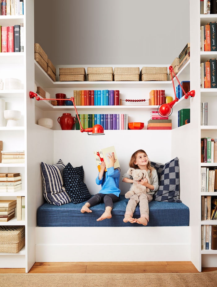 decoration de coin lecture enfant niche murale avec banc à matelas bleu et coussins et bibliotheque murale avec livres