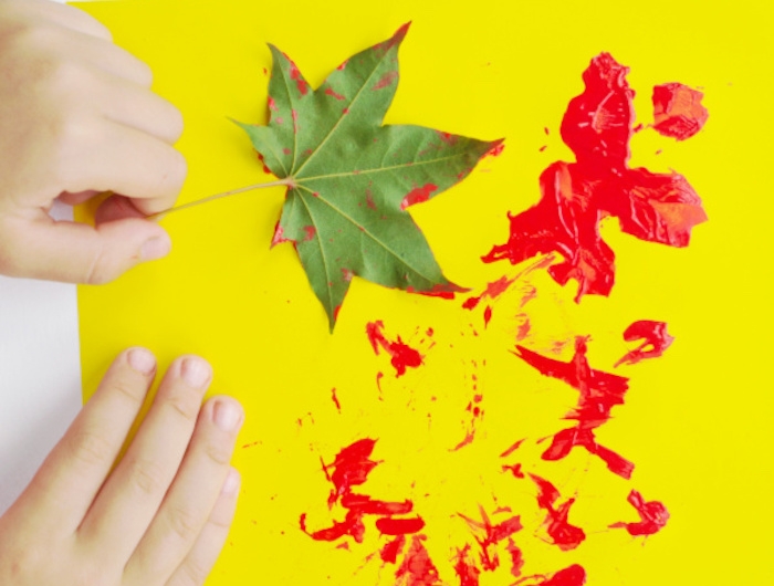 laisser des empreintes colorées de feuilles mortes sur un bout de papier jaune activité peinture pour les 2 3 ans
