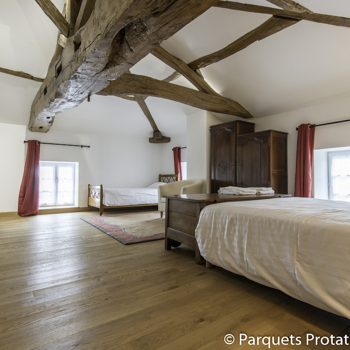 parquet en bois massif pour aménager une chambre rustique avec mobilier de bois brut et des murs blancs