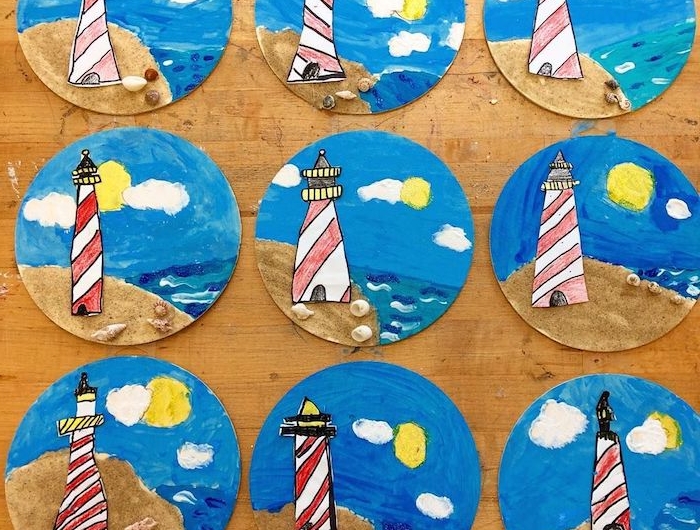phare de papier sur assiette repeinte en bleu avec du sable en bas et coquilles de mer sur sable pois colorés de peinture imitation soleil et nuages