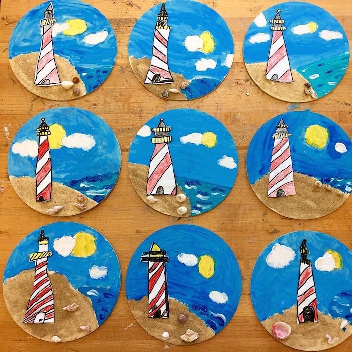 phare de papier sur assiette repeinte en bleu avec du sable en bas et coquilles de mer sur sable pois colorés de peinture imitation soleil et nuages