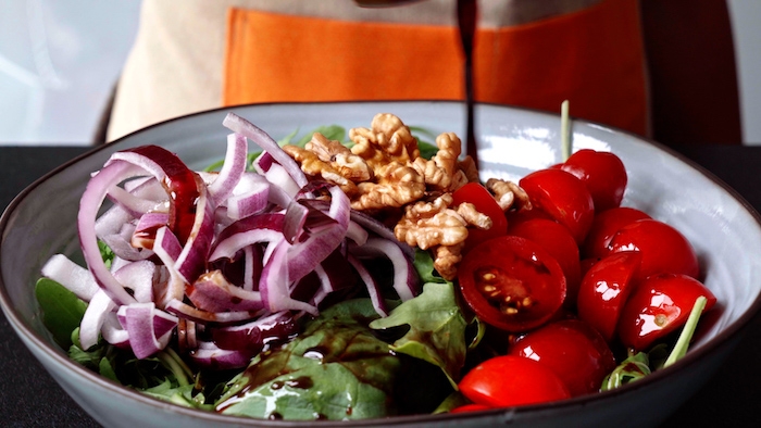 salade printemps été simple verser vinaigrette pour épicer salade roquette et épinards avec tomates cerises et oignons rouges