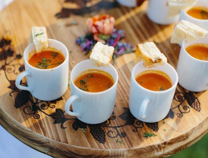 soupe froid dans une tasse à café avec basilic frais et tranche de pain sur planche de bois avec des légumes au centre