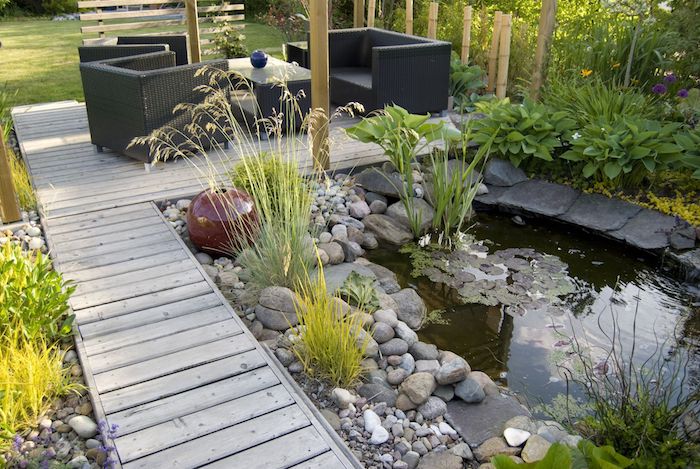 amenagement pation exterieur salon de jardin avec bassin exterieur entouré de pierres et des végétaux simples chemin de jardin en bois