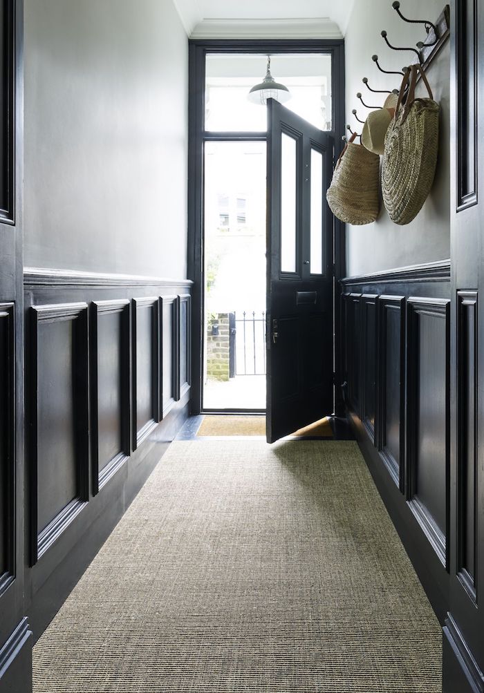 aménagement couloir soubassement bois repeint de noir et porte noire tapis gris et peinture murale blanche