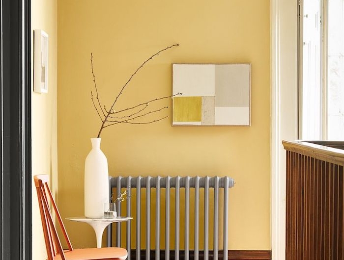 aménagement coulour sur palier avec radiateur gris chaise bois murs jaunes tapis géométrique sur parquet bois brut