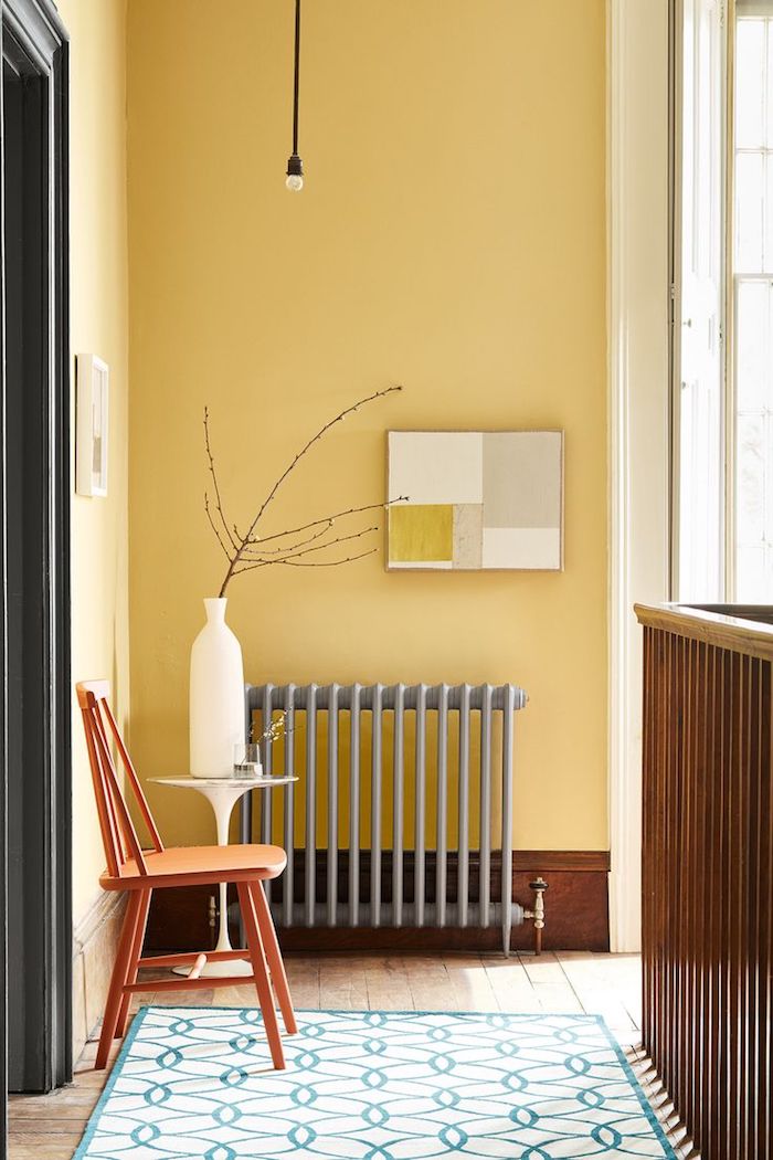 aménagement coulour sur palier avec radiateur gris chaise bois murs jaunes tapis géométrique sur parquet bois brut